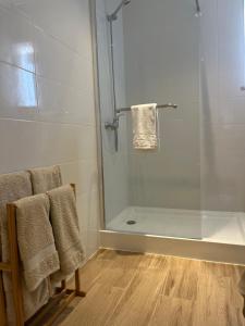 a bathroom with a glass shower with towels and a tub at Vila Glória Guesthouse in Lagos