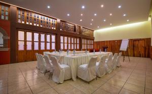 Habitación grande con mesa larga y sillas blancas. en Hotel la Parroquia, en Pátzcuaro