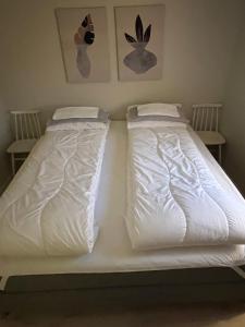 2 camas en un dormitorio con sábanas y almohadas blancas en Lena Apartment Tromsø en Kvaløya
