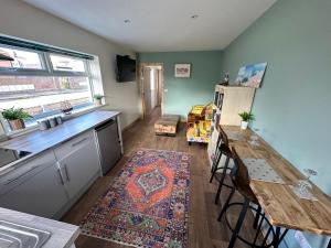 a kitchen with a counter and a table and a refrigerator at Seashell Cottage - Dog friendly 1 bed cottage close to the sea in Hornsea