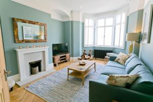 a living room with a blue couch and a fireplace at Eryl Mor in Menai Bridge