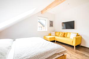 um quarto com uma cama e um sofá amarelo em Apartments Schöneben em Ulrichsberg