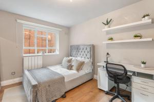 a bedroom with a bed and a desk and a chair at Central Whitechapel - Steps from Station & Sights! in London