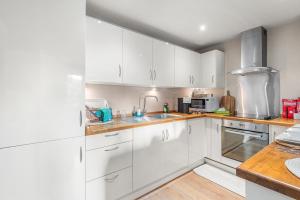 a kitchen with white cabinets and a sink at Central Whitechapel - Steps from Station & Sights! in London