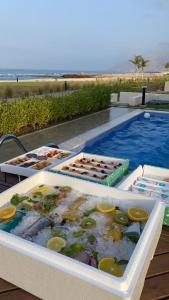 een zwembad met verschillende dienbladen eten op een tafel bij Water Front Villa BF108 in Muscat