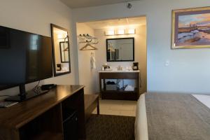 a hotel room with a bed and a flat screen tv at Riviera Motor Lodge in Saratoga