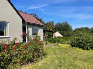 a house with red flowers in the yard at Cozy Garden Glamping in Svendborg