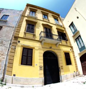 un edificio giallo con porta e finestre nere di Al 22 Appartamenti a Trapani