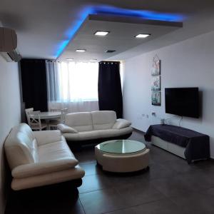a living room with white furniture and a tv at yael house in Ashkelon
