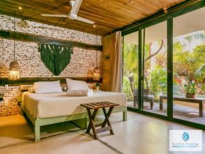 1 dormitorio con cama y pared de ladrillo en Suites Tulum en Tulum