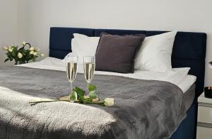 two glasses of champagne are sitting on a bed at URBAN APARTMENTS Premium DOWNTOWN Opolska 10 No 77A with GARAGE in Katowice