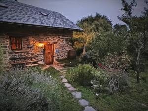 une maison en pierre avec une porte en bois dans un jardin dans l'établissement Dríade, à Villar de las Traviesas