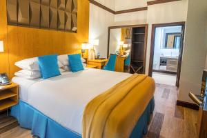 um quarto com uma cama grande com lençóis azuis e amarelos em Sago Palm Hotel em Ocho Rios