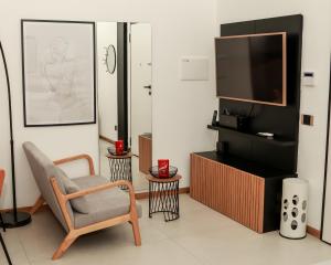 a living room with a chair and a television at Dislocati BnB - Jacuzzi privata - Cucina - TV60" - Minimal Luxury in Marigliano