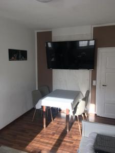 a dining room with a white table and a tv on the wall at Temporary Living - Rest and Relax in Eisenach