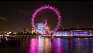 Una rueda de la fortuna iluminada en púrpura por la noche en Mr Charing, en Londres