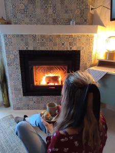 a woman sitting on the floor with a cup of coffee in front of a fireplace at Apartamento Costa de Madrid in Madrid