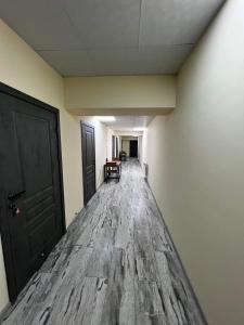 un pasillo vacío con suelo de madera y puerta negra en Pyunic Hotel en Ereván
