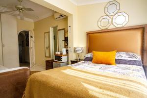 a bedroom with a large bed with a yellow pillow at La Loggia Bed and Breakfast in Durban