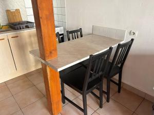 cocina con mesa y 2 sillas negras en T1 en duplex, en La Riche