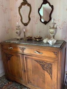 a wooden dresser with two vases and a mirror at Byhus - det genuina Frankrike in Laurens
