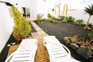 twee witte stoelen op een patio met planten bij Casa Tabaiba in Tías