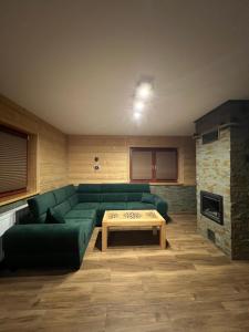 - un salon avec un canapé vert et une table dans l'établissement Apartament i Pokoje u Łowisza, à Ciche
