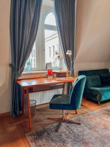 ein Wohnzimmer mit einem Schreibtisch und einem grünen Stuhl in der Unterkunft Apartmenthaus am Dom "Maisonette" in Zwickau