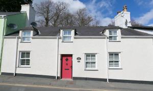 ein weißes Haus mit einer roten Tür auf einer Straße in der Unterkunft Gower Cottage in Beaumaris