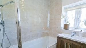 y baño con ducha, bañera y lavamanos. en Gower Cottage en Beaumaris