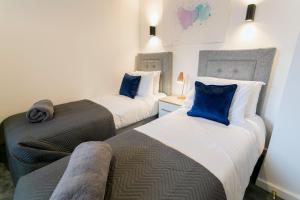 two beds with blue pillows in a room at Gwel y Fenai in Penmon