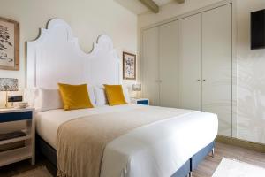 una camera da letto con un grande letto bianco con cuscini gialli di La Rosa de la Alfalfa a Siviglia