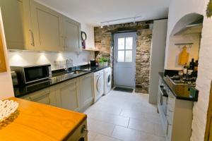 a kitchen with white appliances and a stone wall at Melvin Cottage in Beaumaris
