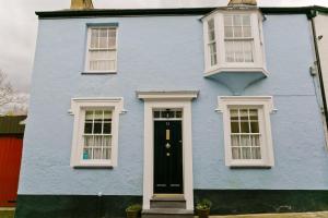a blue house with white windows and a black door at Melvin Cottage in Beaumaris
