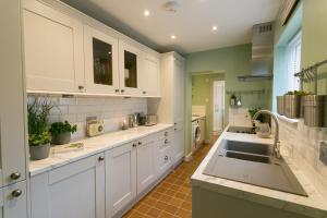 a large kitchen with white cabinets and a sink at Hyfrydle in Beaumaris +5 photos