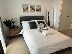 a bedroom with a large white bed with a night stand at My Apartment Brixton - Modern Double Room with En-suite in London