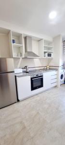 eine Küche mit weißen Schränken, einem Herd und einem Kühlschrank in der Unterkunft Piso 2 Dormitorios. WIFI in Pontevedra