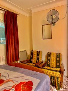 Comfort Sea view serviced apartment near montaza palace and Easy access to all Sites è AC ,WIFI, Security في الإسكندرية: غرفة نوم بسرير وكرسيين ومروحة