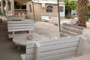 a group of white wooden tables and chairs at חצר הצ'אנס - בקתות להשראה in Almog