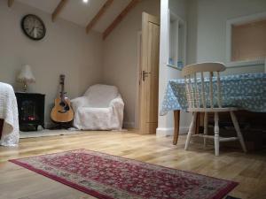 a room with a table and a chair and a guitar at Lovely cottage in Lower Bracky