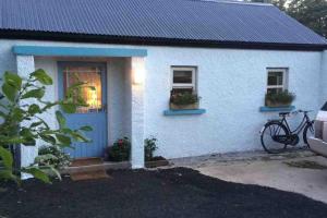 a white house with a bike parked in front of it at Lovely cottage in Lower Bracky
