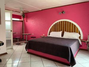 una camera da letto con un grande letto con una parete rosa di Mesón Yollotl a Puebla