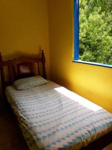 uma cama num quarto amarelo com uma janela em Quarto na floresta com saída no igarapé - Espaço Caminho das pedras em Alter do Chão