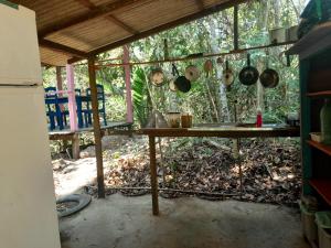 cocina con mesa, ollas y sartenes en Quarto na floresta com saída no igarapé - Espaço Caminho das pedras en Alter do Chao