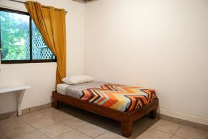 ein kleines Bett in einem Zimmer mit Fenster in der Unterkunft Casa Sarah in Nosara