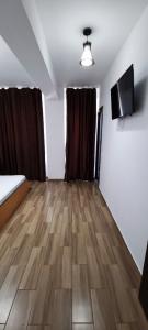 een kamer met een houten vloer en een flatscreen-tv bij Hotel Blue Sky Resort in Eforie Nord