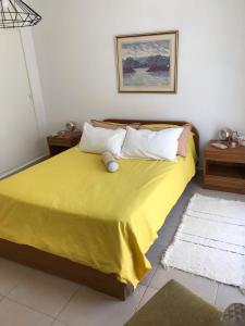 1 dormitorio con 1 cama con sábanas y almohadas amarillas en Complejo Los Aromitos 1 en Río Ceballos