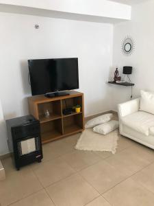 sala de estar con TV y sofá blanco en Complejo Los Aromitos 1 en Río Ceballos