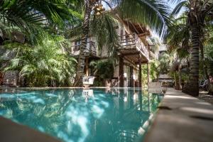 una piscina frente a un edificio con palmeras en Suites Tulum, en Tulum