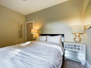 a bedroom with a large white bed and two lamps at Stoneswood Cottage & Garden, Delph, Saddleworth in Delph